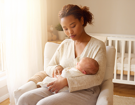 Mãe segurando bebê recém-nascido em quarto iluminado, expressão serena, representando o toc perinatal e os pensamentos intrusivos na maternidade