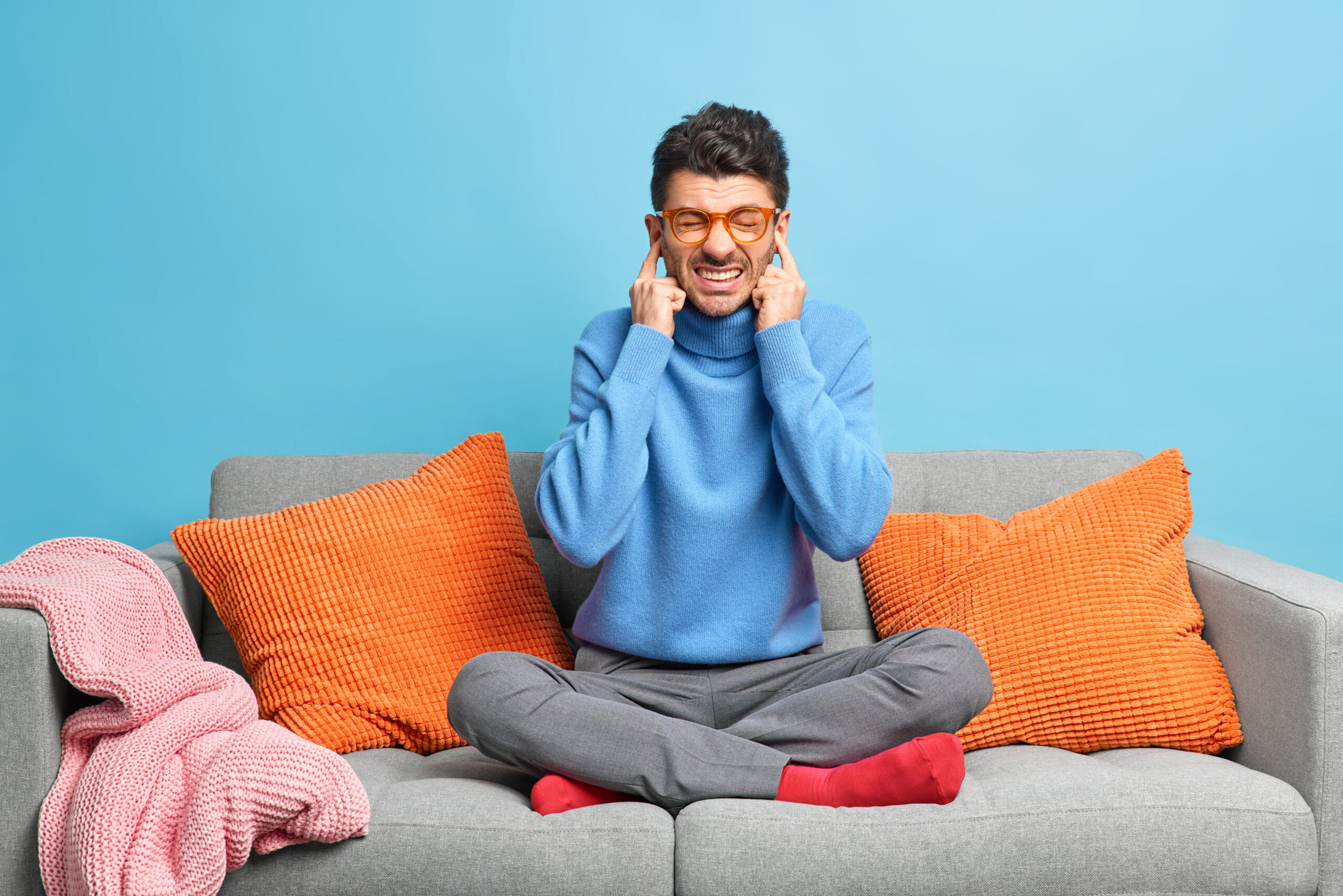 Adulto cobrindo os ouvidos em casa, representando a sobrecarga sensorial no autismo em adultos