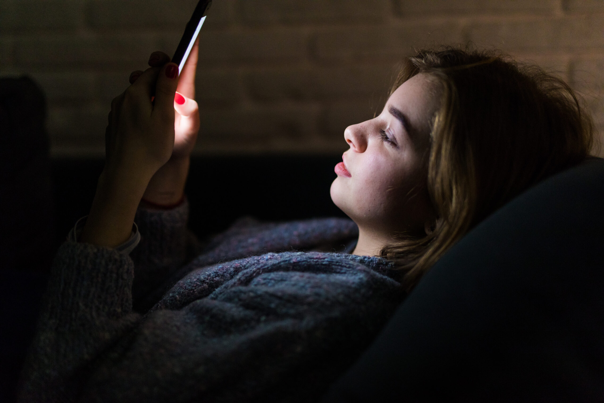 Jovem no sofá à noite usando o celular, ilustrando redes sociais e saúde mental
