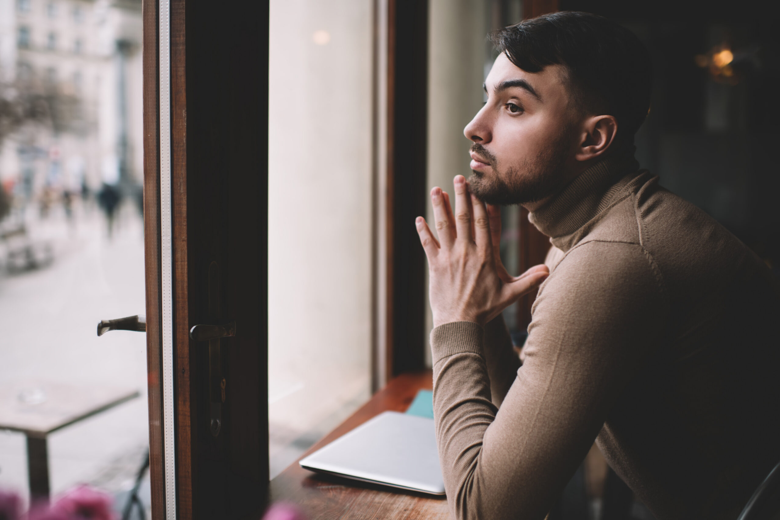 Homem pensativo olhando pela janela representando ruminação mental